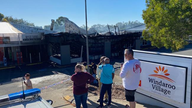 Locals gather in front of the fire-damaged shops at the Windaroo Village centre. Picture: Peter Wallis