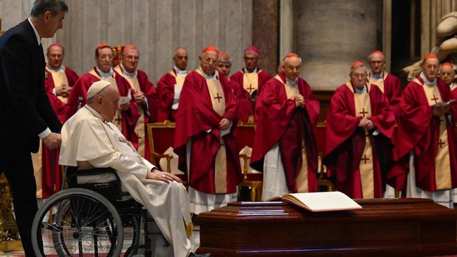 Pope Francis is pushed on a wheelchair by the coffin of Cardinal George Pell, during a funeral mass in the St Peter’s Basilica at the Vatican. Picture: AFP