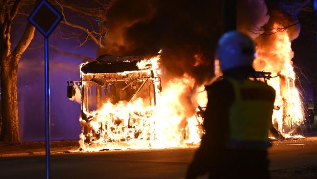 A police officer stands next to a city bus burning in Malmo on April 16 after rioting in response to a demonstration by Rasmus Paludan, leader of the Danish right-wing extremist party Tight Course. Picture: AFP