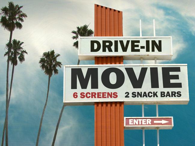 aged and worn drive in movie sign with palm trees