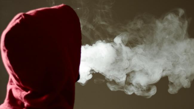 Young male in red hoodie vaping smoking, exhales thick vapor, isolated rear view Picture: iStock