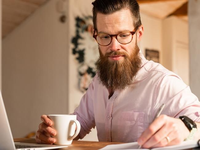 A man sitting at home, using his laptop to search for a new job.