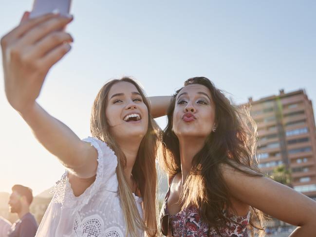 Portrait of two happy women taking selfie on beach having fun