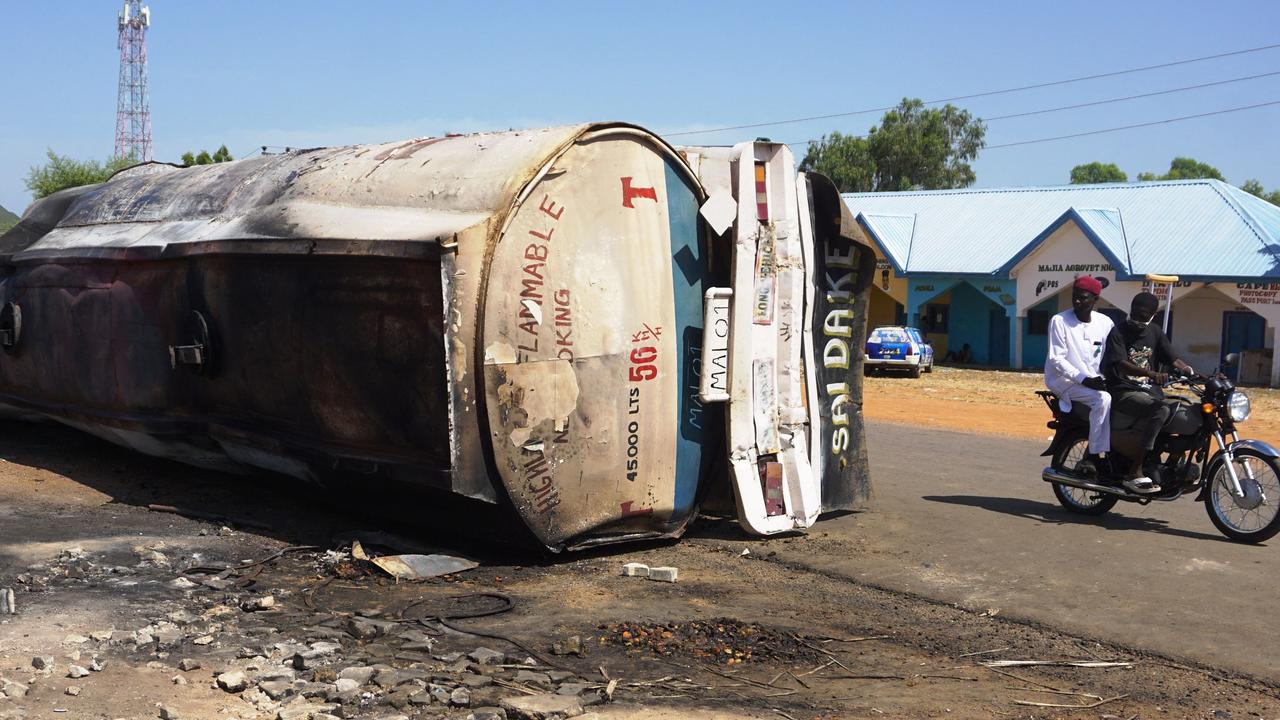 A motorcycle rides past the remain of a fuel tanker whose explosion killed almost 150 people in. An explosion tore through crowds of people who had rushed to collect fuel spilling from a crashed tanker in northern Nigeria. (Photo by Aminu ABUBAKAR / AFP)