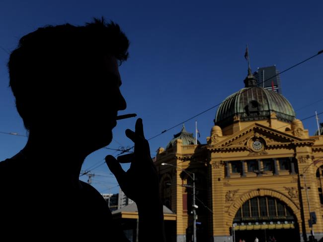 A man smokes a cigarette outside Flinders Street Station in Melbourne, Thursday, May 15, 2014. Melbourne's city centre could become completely smoke-free within three years after a cigarette ban in a laneway was dubbed a success. (AAP Image/Julian Smith) NO ARCHIVING