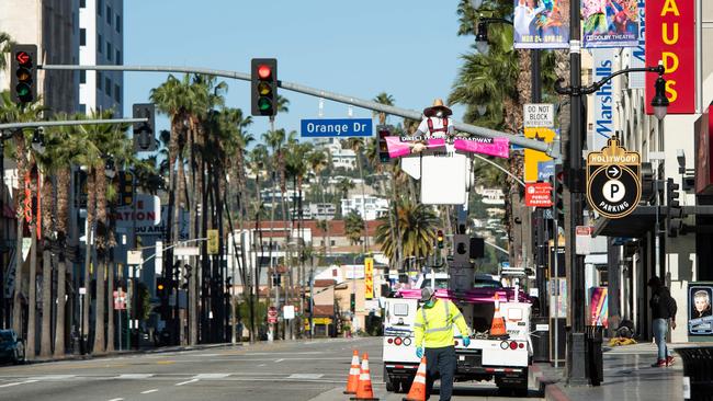 A worker changes the posters on an empty Hollywood Blvd amid the coronavirus pandemic on April 15, 2020 in Los Angeles, California. Picture: Valerie Macon / AFP.