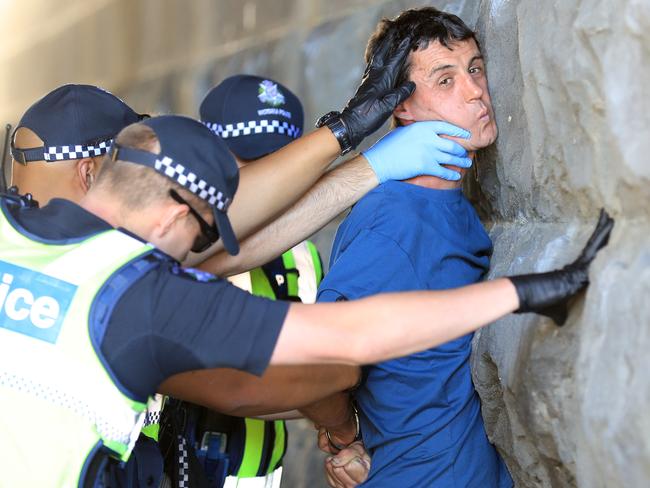 Police officers question the man before he is forced up against Princess Bridge and searched. Picture: Alex Coppel