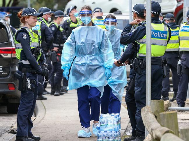 Medical staff wearing PPE holding material about to walk into the Flemington Public housing flats in 2020. Picture: Asanka Ratnayake