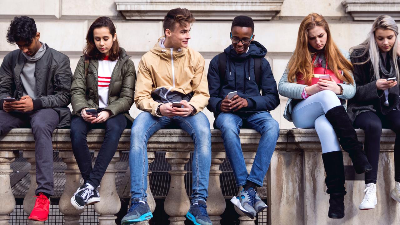 Teenage students using smartphones on a school break.