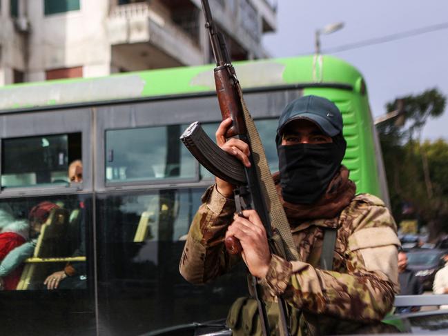 A fighter affiliated with Syria's new administration gestures with his rifle in Syria's western coastal city of Latakia on December 26, 2024. Syria's new authorities launched an operation in a stronghold of ousted president Bashar al-Assad on December 26, with a war monitor saying three gunmen affiliated with the former government were killed, a day after angry protests erupted in several areas around Syria over a video showing an attack on an Alawite shrine that circulated online. (Photo by AAREF WATAD / AFP)