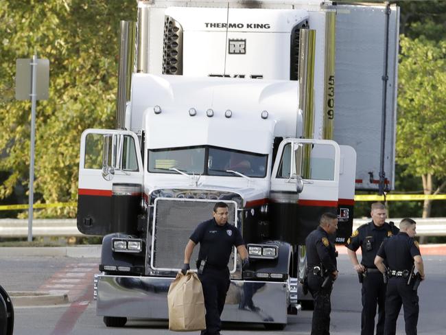 San Antonio police officers investigate the scene Sunday, July 23, 2017, where eight people were found dead in a tractor-trailer loaded with at least 30 others outside a Walmart store in stifling summer heat in what police are calling a horrific human trafficking case,  in San Antonio. (AP Photo/Eric Gay)