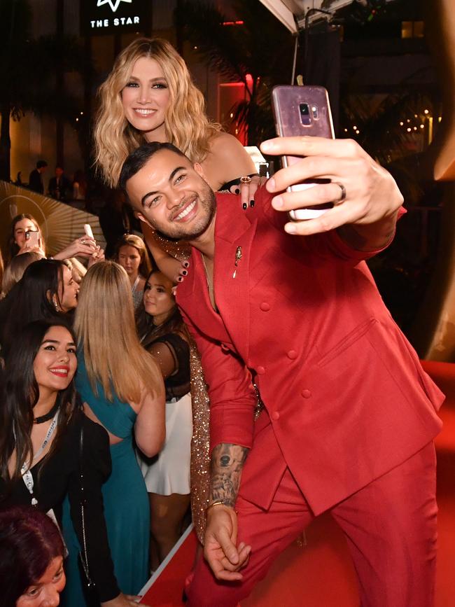 Guy Sebastian and Delta Goodrem posing for selfie photographs with fans. Picture: AAP