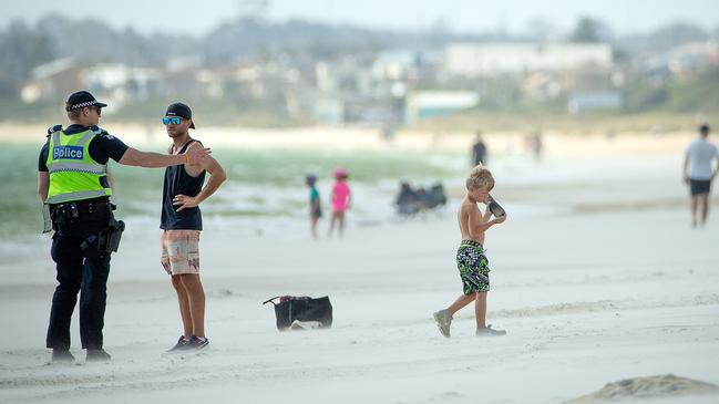 Police speak to people at the beach. Picture: Mark Stewart