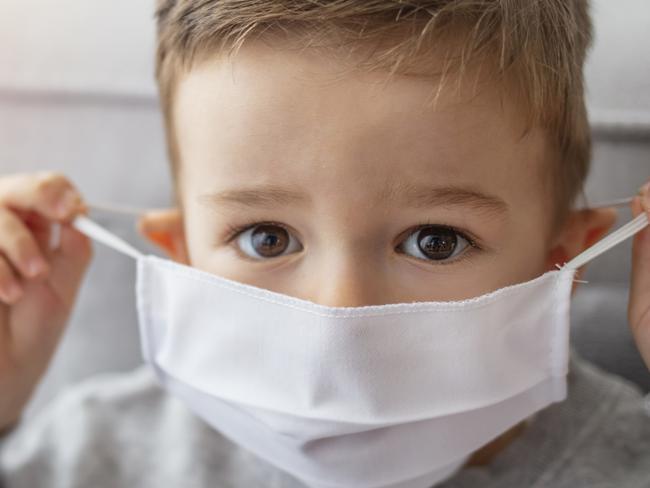 Young child wearing a respiratory mask as a prevention against the Coronavirus Covid-19. Little boy wearing anti virus mask staying at home. Protection against flu and virus infection