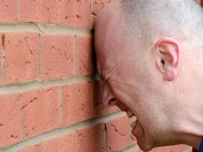 a man banging his head agaist the wall in frustration