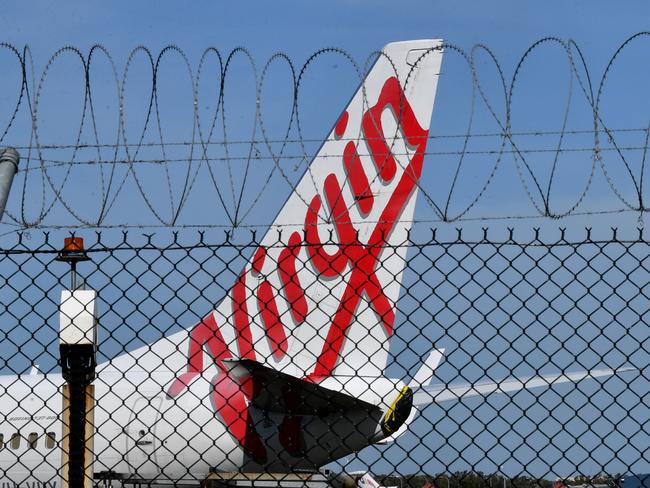 A grounded Virgin Australia aircraft is seen parked at Brisbane Airport in Brisbane, Friday, April 17, 2020. The Australian government has forced airline carriers to cut both their domestic and international flights in order to slow the spread of the coronavirus (COVID-19) disease. (AAP Image/Darren England) NO ARCHIVING