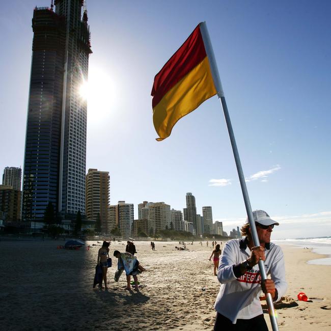 A lifeguard erects a red and yellow flag at Surfers Paradise.