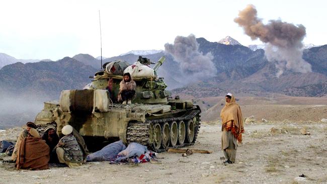 Afghan anti-Taliban fighters sit around a Russian T-55 tank while two bombs explode following an attack by American B-52 bombers on al-Qa’ida positions in Tora Bora in December 2001. Picture: AFP