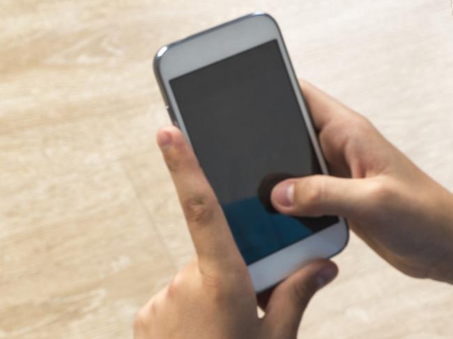 Boy touching a mobile phone with his back to camera