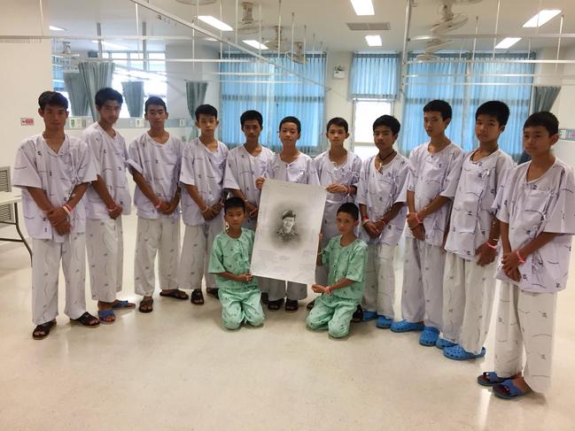 The Wild Boars team at hospital in Chiang Rai province posing after writing messages on a drawing of former Navy SEAL diver Saman Kunan who died on July 6 during the rescue mission. Picture: AFP