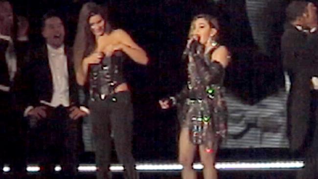 The girl quickly covers up after having her top pulled down by Madonna on stage. Picture: Splash News
