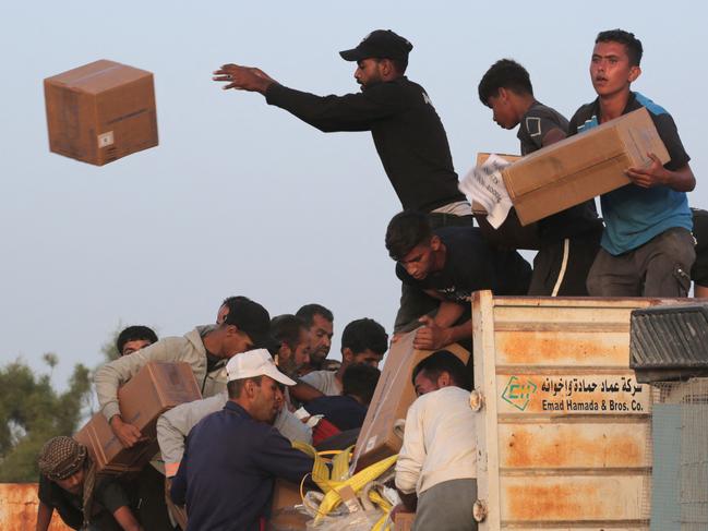 TOPSHOT - Palestinians carry boxes of humanitarian aid after rushing the trucks transporting the international aid from the US-built Trident Pier near Nuseirat in the central Gaza Strip on May 18, 2024, amid the ongoing conflict between Israel and the militant group Hamas. (Photo by AFP)