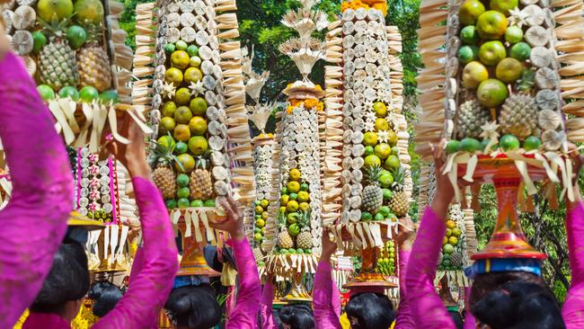 Women in traditional Balinese people costume sarong carry hindu religious offering during ceremony on parade at art and culture festival.