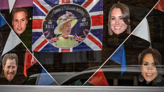 A flag and face masks of members of the royal family are displayed in the window of the Blue Anchor pub in London. Picture: Getty Images.