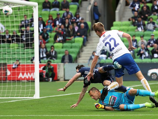 Robbie Kruse of Melbourne Victory scores as he crashes into Glen Moss and Lachlan Jackson of Newcastle Jets. Picture: AAP Image/George Salpigtidis