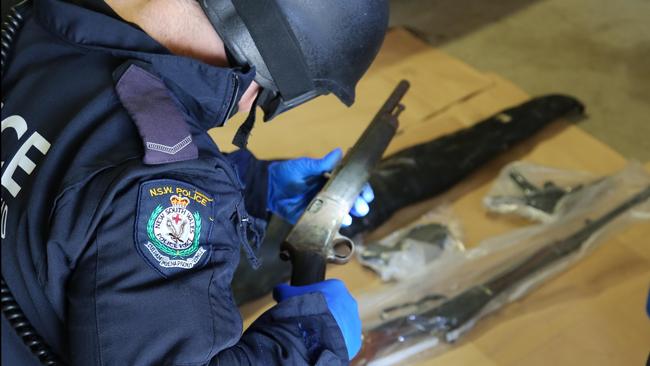 A Sydney police officer seizes firearms as part of a 2016 strike force. Picture: Police NSW