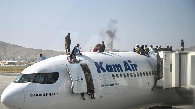 Afghan people climb on to a plane as they wait at Kabul International Airport. Picture: AFP