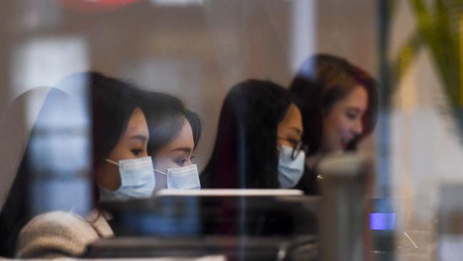 Tellers wearing face masks work at a currency exchange store in Melbourne. Picture: William West/AFP