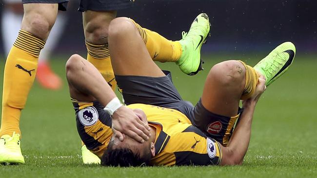 Arsenal's Alexis Sanchez holds his right ankle after sustaining an injury.