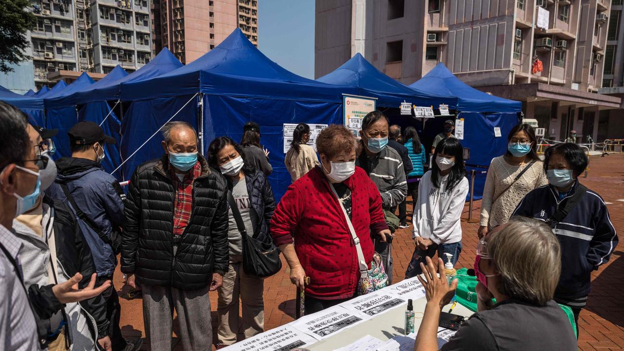 People speak to a worker at a registration desk of a Hong Kong mobile station providing the BioNTech Covid-19 coronavirus vaccine. Picture: AFP.