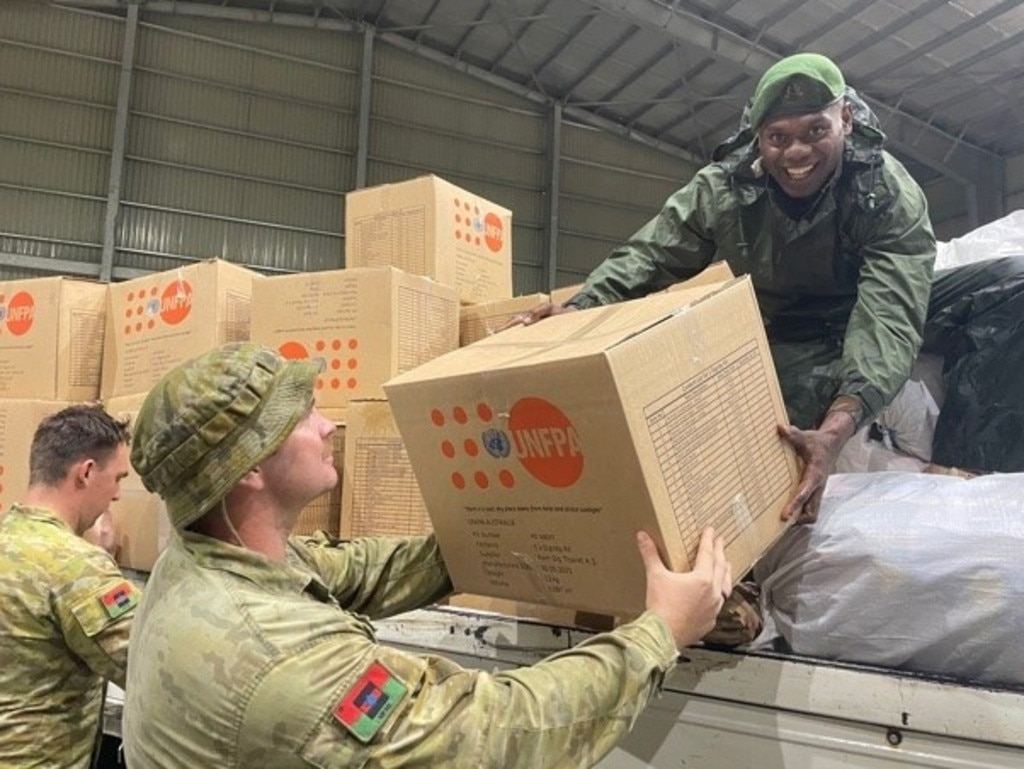 Australian Defence Force Private Zed Barrett (left) and Private Luke Smith (centre) assist a member of the Vanuatu Mobile Force with the unloading aid in Port Vila, Vanuatu this year.