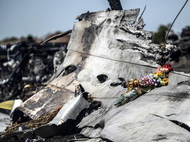 (FILES) This photograph shows flowers, left by parents of an Australian victim of the crash on a piece of the Malaysia Airlines flight MH17, near the village of Hrabove (Grabove), in the Donetsk region on July 26, 2014. The families of the victims of the downing of flight MH17 in war-torn eastern Ukraine are this week commemorating ten years since the tragedy, with dwindling hopes of seeing those responsible behind bars. (Photo by Bulent KILIC / AFP)