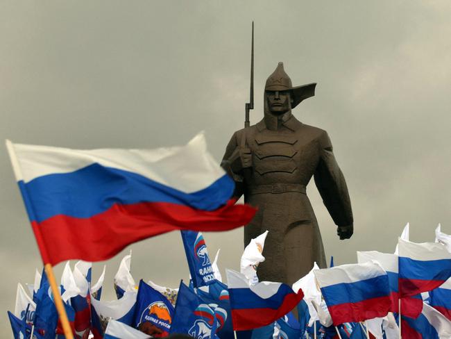 (FILES) Pro-Kremlin activist hold Russian flags near a monument to Red Army soldier as they rally in the southern Russian city of Stavropol, on March 18, 2014, to celebrate the incorporation of Crimea. President Vladimir Putin  pushed today every emotional button of the collective Russian psyche as he justified the incorporation of Crimea, citing everything from ancient history to Russia's demand for respect to Western double standards. Ukraine has been locked in an existential fight for its freedom ever since Russia sent armed soldiers with no insignia, dubbed the "little green men", to take over the Crimea peninsula on February 28, 2014, following a pro-EU revolution in Kyiv. The annexation of Crimea marked the beginning of a decade of aggression against its ex-Soviet neighbour. (Photo by DANIL SEMYONOV / AFP)