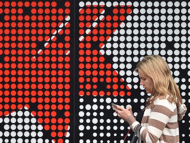 (FILES) In this file photo taken on November 1, 2017 a woman walks past a National Australia Bank (NAB) branch in Sydney. National Australia Bank announced plans to sell down its wealth management arm on May 3, 2018 as it continues to offload assets to simplify its business.  / AFP PHOTO / PETER PARKS