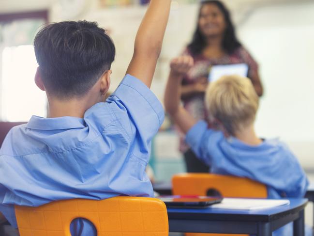 Aboriginal Elementary school  teacher giving a presentation to the class. The students have their hands raised to ask  questions in the classroom Picture:  Istock