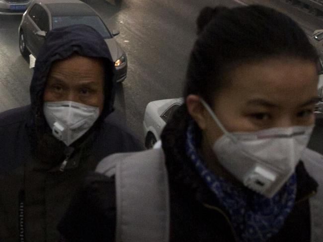 FILE - In this file photo taken Saturday, Nov. 29, 2014, pedestrians wear masks against the pollution as they cross an overhead bridge over a busy highway in Beijing, China. A slick new documentary on China's environmental woes has racked up more than 175 million online views in two days, underscoring growing concern in the country over the impact of air, water and soil pollution. Costing about $160,000 to make, the documentary won praise Sunday March 1, 2015, from new Chinese Environment Minister Chen Jining. (AP Photo/Ng Han Guan, File)