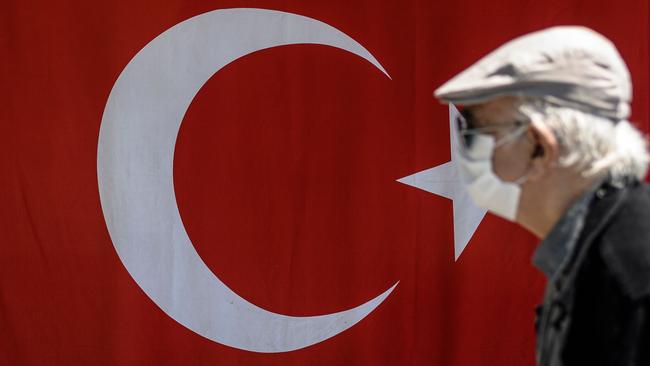 An elderly man wearing a protective face mask, walks past the Turkish flag. Earlier this month Turkish people aged 65 and over described their joy after the government allowed them to go outside for the first time in nearly two months in an easing of the coronavirus restrictions. Picture: Ozan Kose/AFP