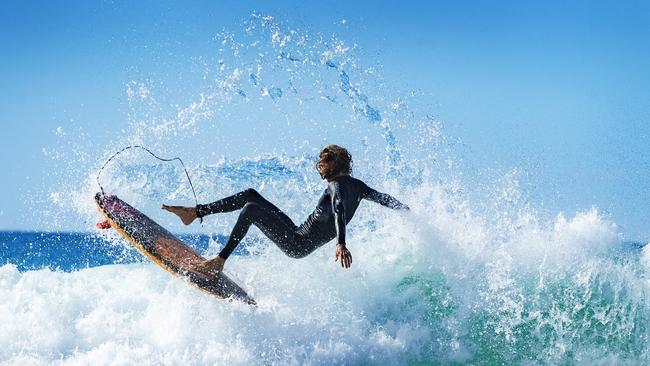 A Surfer balances on one foot at Sunshine Beach as westerly winds brings cool weather and perfect beach days to south east Queensland. Picture: Lachie Millard