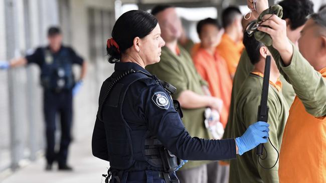 An officer scans prisoners with a metal detector after their shift in the workshops. Picture: Patrick Woods.