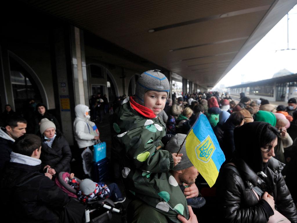 A man holds a boy with the Ukrainian flag as they wait for a train on a platform at Kyiv's railway station. Picture: AFP