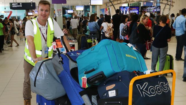 Gold Coast Airport CEO Chris Mills loading luggage during one of the busiest days ever for the airport. Picture: Glenn Hampson