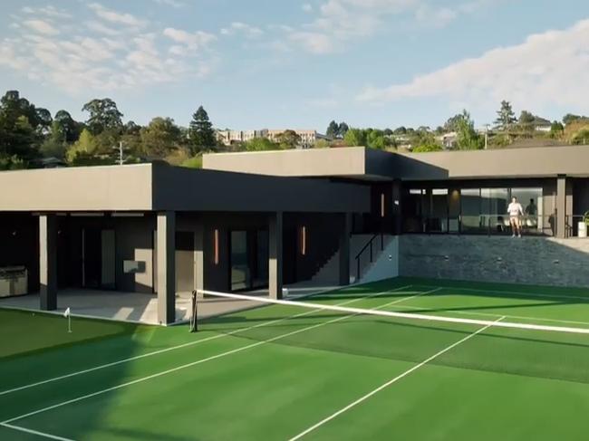 The all-black mansion is fit with a large tennis court.