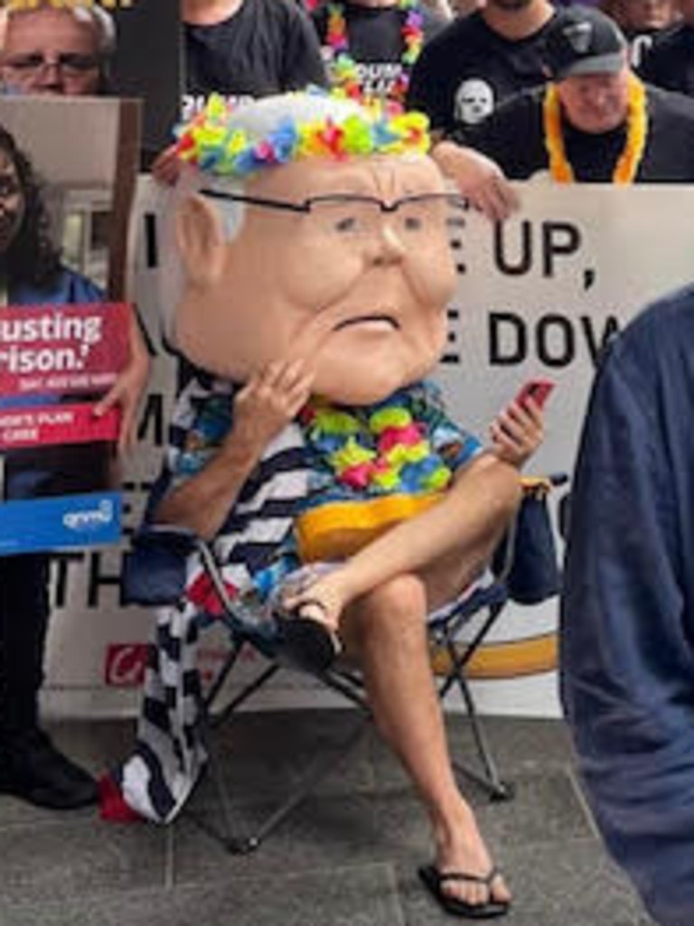 A man wearing a comically large Scott Morrison head and dressed in a Hawaiian shirt and a towel was seen at Sunday's protest in Brisbane