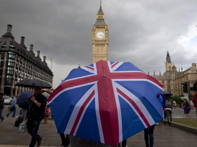 TOPSHOT - A pedestrian shelters from the rain beneath a Union flag themed umbrella as they walk near the Big Ben clock face and the Elizabeth Tower at the Houses of Parliament in central London on June 25, 2016, following the pro-Brexit result of the UK's EU referendum vote. The result of Britain's June 23 referendum vote to leave the European Union (EU) has pitted parents against children, cities against rural areas, north against south and university graduates against those with fewer qualifications. London, Scotland and Northern Ireland voted to remain in the EU but Wales and large swathes of England, particularly former industrial hubs in the north with many disaffected workers, backed a Brexit. / AFP PHOTO / JUSTIN TALLIS