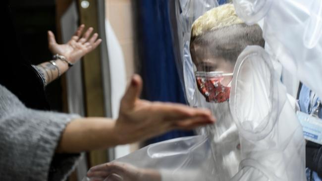 A boy patient prepares to hug his mother through plastic protection at the San Raffaele hospital in Rome. Picture: AFP