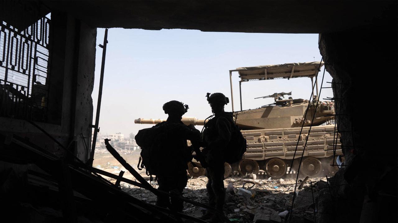 Israeli soldiers standing inside a building near a main battle tank as part of the activity of the 99th Division in the Zaytoun Area of Gaza. Picture: AFP